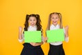 Homework done. Happy small children holding empty homework sheets on yellow background. Cute little girls smiling with