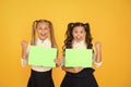 Homework done. Happy small children holding empty homework sheets on yellow background. Cute little girls smiling with