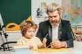 Homework help. Father helping his son to make homework. Elementary school. Pupil learning letters and numbers. Royalty Free Stock Photo