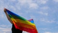Transgender holding LGBT flag on sky background