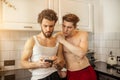 Homosexual couple in kitchen at morning, with mobile phone