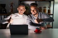 Homosexual couple using computer laptop approving doing positive gesture with hand, thumbs up smiling and happy for success Royalty Free Stock Photo