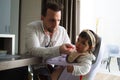 Homosexual father feeding the porridge to the little daughter sitting in his chair Royalty Free Stock Photo