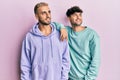 Homosexual gay couple standing together wearing casual clothes looking away to side with smile on face, natural expression Royalty Free Stock Photo