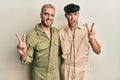 Homosexual gay couple standing together wearing casual jumpsuit smiling with happy face winking at the camera doing victory sign Royalty Free Stock Photo