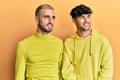 Homosexual gay couple standing together wearing yellow clothes looking away to side with smile on face, natural expression Royalty Free Stock Photo