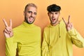 Homosexual gay couple standing together wearing yellow clothes smiling with happy face winking at the camera doing victory sign Royalty Free Stock Photo