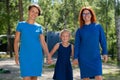 Homosexual lesbian couple hold daughter`s hands. A girl walks with two mothers in the park. Two married women and a