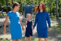 Homosexual lesbian couple hold daughter's hands. A girl walks with two mothers in the park. Two married women and a