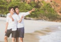 Homosexual portrait young asian couple standing pointing something together on beach in summer Royalty Free Stock Photo