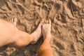 Homosexual relationship concept. Male hairy foot touching other male foot on the beach, top view. Hidden touching each other