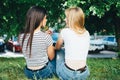 Homosexual women embrace and laugh while sitting on the grass.