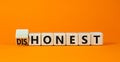 Honest or dishonest symbol. Turned cube and changed the concept word Dishonest to Honest. Beautiful orange table orange background