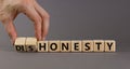 Honesty or dishonesty symbol. Businessman hand turns a cube and changes the word `dishonesty` to `honesty`. Beautiful grey