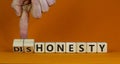 Honesty or dishonesty symbol. Businessman hand turns a cube and changes the word `dishonesty` to `honesty`. Beautiful orange Royalty Free Stock Photo