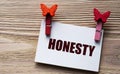 HONESTY - word on a white sheet with beautiful clothespins on a wooden background