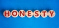 Honesty word written on wood circles. Honesty text on table, business concept. Beautiful blue background. Copy space