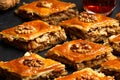 Honey baklava with walnuts on black slate. Portions of oriental sweets. Turkish sugary pieces. Tea poured in armudu glass in the Royalty Free Stock Photo