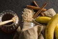 Honey, banana, oatmeal, cinnamon sticks on black background