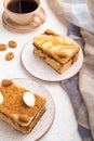 Honey cake with milk cream, caramel, almonds and a cup of coffee on a white concrete background. Side view, close up Royalty Free Stock Photo