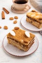 Honey cake with milk cream, caramel, almonds and a cup of coffee on a white concrete background. Side view, close up Royalty Free Stock Photo