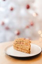 Honey cake on the table near the white Christmas tree with golden bokeh lights Royalty Free Stock Photo