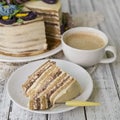 Honey cake on a white table with cup of coffe. Cake with cream flowers. Close up, copy space. Royalty Free Stock Photo