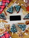 Honey cakes decorated as Christmas trees and a smartphone with an empty screen in the middle Royalty Free Stock Photo