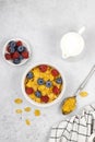 Honey corn flakes with berries: raspberries, blueberries, milk, spoon on a gray background, top view. Royalty Free Stock Photo