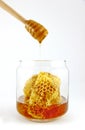 Honey dipper with fresh honey and honeycomb in glass jar Royalty Free Stock Photo