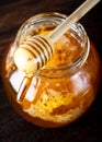 Honey dipper pouring honey in the jar. Wooden honey dipper taking honey from the jar.