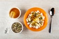 Honey dipper on bowl with honey, bowl with pumpkin seeds, sesame, sunflower seeds and flax seeds, bowl with cottage cheese, honey