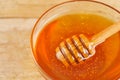 Honey dripping from honey dipper in glass bowl. Thick honey dipping from the wooden honey spoon, closeup.