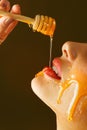 Honey dripping from honey dipper on sexy girl lips. Thick honey dipping from the wooden honey spoon. Beauty model woman Royalty Free Stock Photo