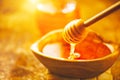Honey dripping from honey dipper in wooden bowl. Healthy organic thick honey pouring from the wooden honey spoon Royalty Free Stock Photo