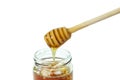 Honey dripping in glass jar and wooden dipper isolated on a white background, concept of bee products Royalty Free Stock Photo