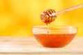 Honey dripping from honey dipper in glass bowl. Thick honey dipping from the wooden honey spoon, closeup.