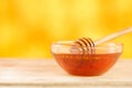 Honey dripping from honey dipper in glass bowl. Thick honey dipping from the wooden honey spoon, closeup.