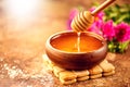 Honey dripping from honey dipper in wooden bowl.  Close-up. Healthy organic thick honey dipping from the wooden honey spoon Royalty Free Stock Photo