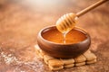 Honey dripping from honey dipper in wooden bowl. Healthy organic thick honey pouring from the wooden honey spoon Royalty Free Stock Photo