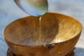 Honey dripping from a metal spoon into a wooden bowl Royalty Free Stock Photo