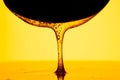 Honey dripping, pouring from dark spoon on yellow background. Thick viscous honey molasses flowing. Close up of golden Royalty Free Stock Photo