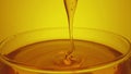 Honey dripping, pouring from spoon in glass. Thick honey molasses dripping into full glass. Close up of golden honey Royalty Free Stock Photo