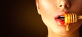 Honey dripping on girl lips from the wooden spoon Royalty Free Stock Photo