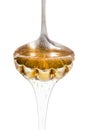 Honey dripping from silver spoon isolated on white Royalty Free Stock Photo