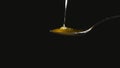 Honey dripping from the stainless tea spoon on black background Royalty Free Stock Photo