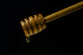 Honey dripping to a honey dipper isolated on a black background. Concept healthy food. Royalty Free Stock Photo