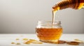 Honey dripping from a wooden honey dipper into a glass jar on a white background Royalty Free Stock Photo