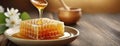 Honey dripping from a wooden dipper onto honeycomb on a plate. Stream of golden honey with white flowers and bowl in the Royalty Free Stock Photo