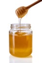 Honey dripping from wooden honey dipper in glass jar Royalty Free Stock Photo